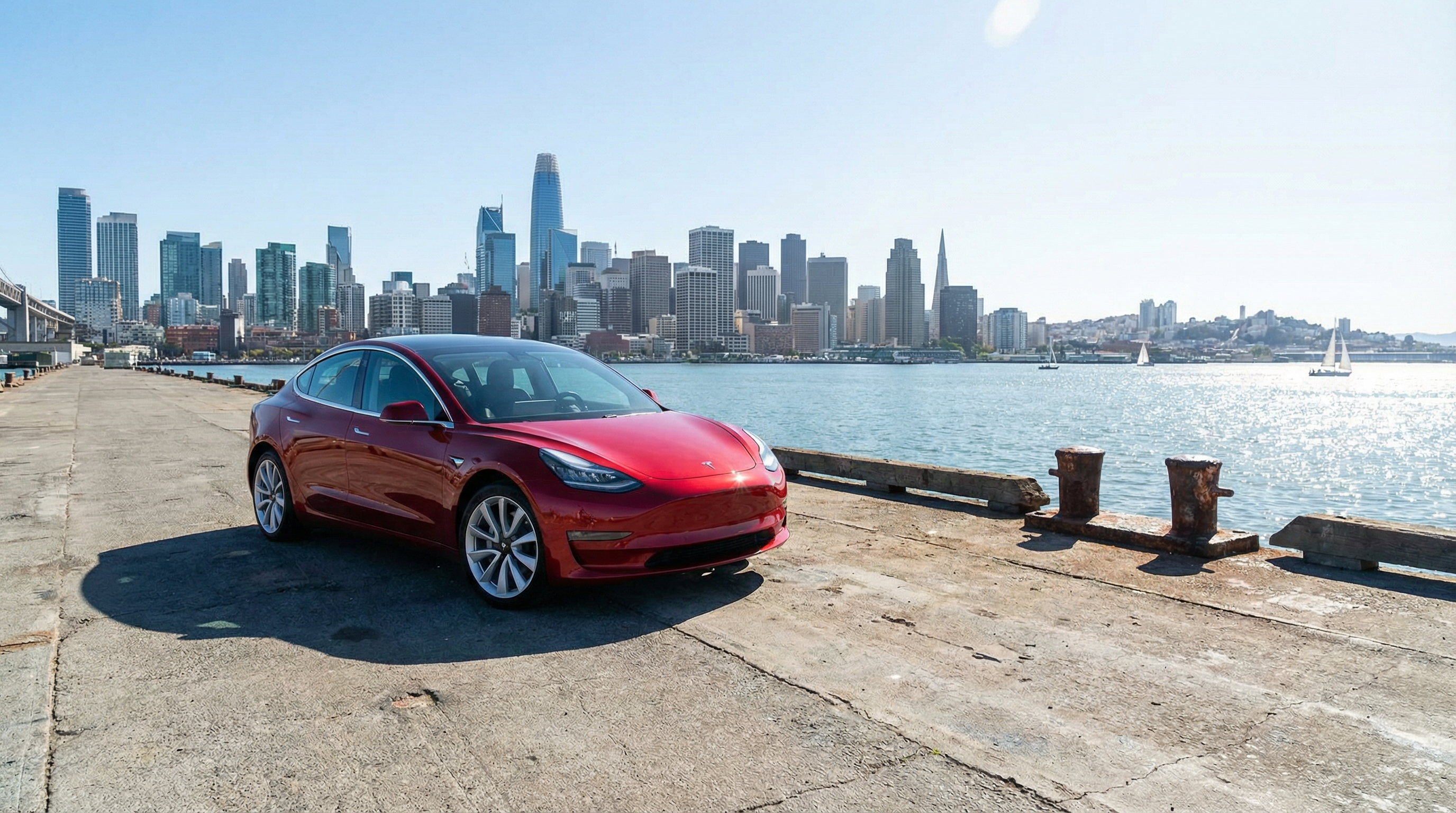 Red Tesla Model 3 on pier with city skyline