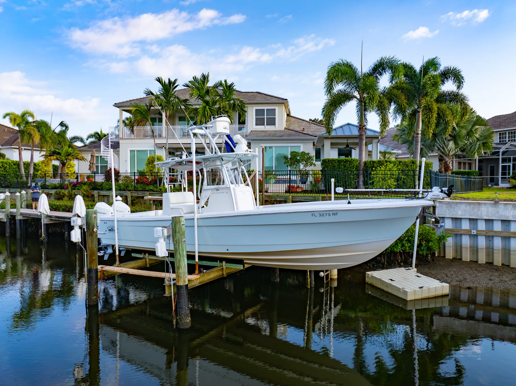 Full side profile of a white center-console boat on a Tampa Bay waterfront lift